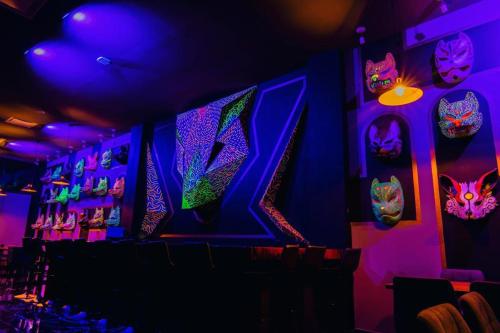 克雷塔罗Hotel Yoru的墙上有紫色灯和面具的房间