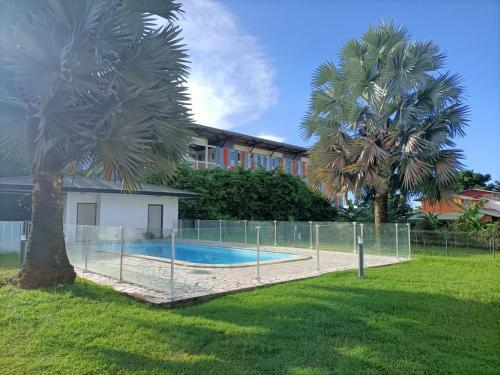 卡宴Beau T3 proche plage secteur Montabo à Cayenne的环绕着两棵棕榈树的游泳池的围栏