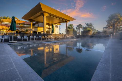 罗托鲁瓦富豪棕榈度假酒店的一个带椅子的游泳池和一座带建筑的建筑