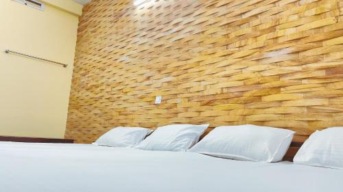 埃尔讷古勒姆PPG HOMES的一张带白色枕头的床铺,靠砖墙
