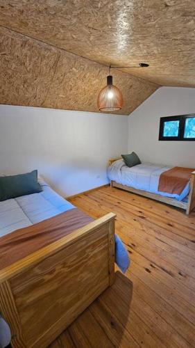 圣萨尔瓦多德朱Cabaña La escondida - JuJuy-的一间卧室设有两张床,铺有木地板