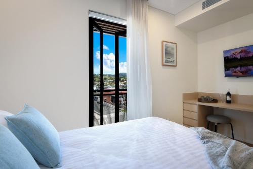 凯阿玛Nova Kiama的一间卧室配有一张床、一张书桌和一个窗户。