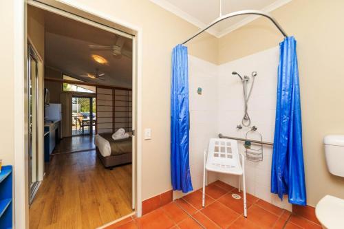 布伦瑞克黑兹Reflections Brunswick Head - Holiday Park的浴室设有蓝色淋浴窗帘和卫生间。