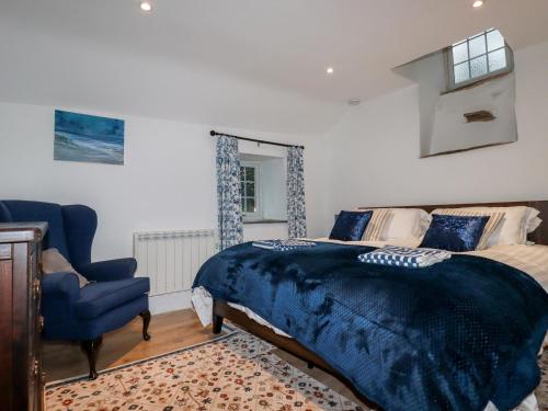 廷塔杰尔Downrow Barn的一间卧室配有一张床和一张蓝色椅子