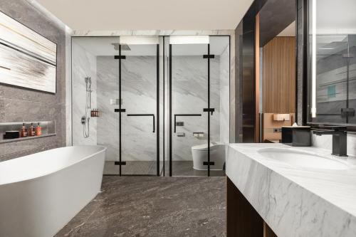 深圳深圳龙华温德姆花园酒店的浴室配有2个盥洗盆、浴缸和淋浴。