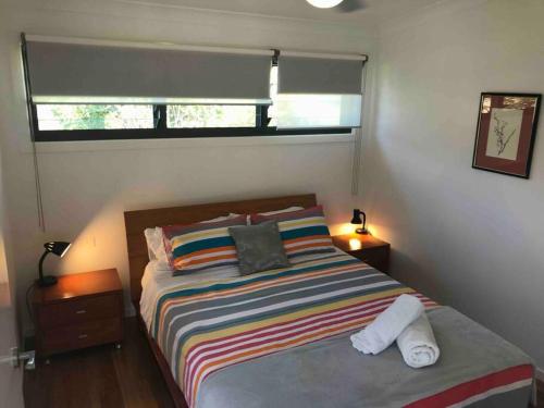 科夫斯港Coffs Harbour Sanctuary的一间卧室配有一张带彩色条纹毯子的床