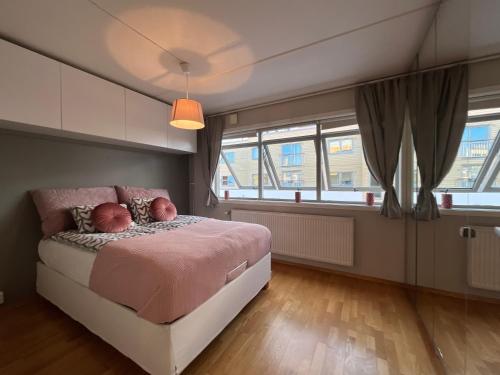 奥斯陆City center flat w roof top terrace & free parking的一间卧室配有一张带粉红色床单和窗户的床。
