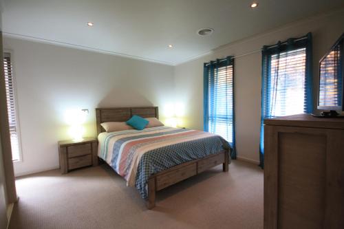 亚斯Yass Valley Stays - Easy self check-in的一间卧室配有带2个床头柜和2个窗户的床