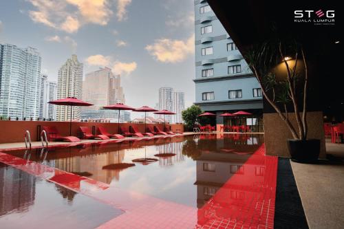 吉隆坡STEG Kuala Lumpur的一座大楼内一个带红色椅子和遮阳伞的游泳池