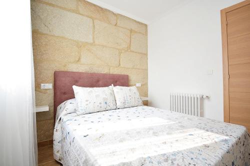 庞特维德拉Casa con jardín en Pontevedra的一间卧室配有一张石墙床