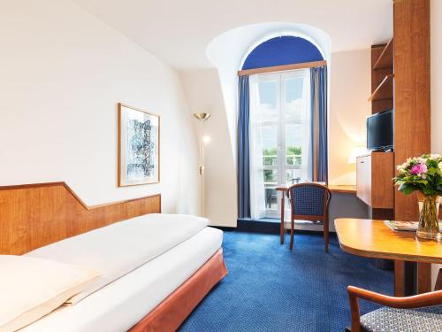 维也纳Living Hotel Kaiser Franz Joseph的酒店客房配有一张床铺和一张桌子。