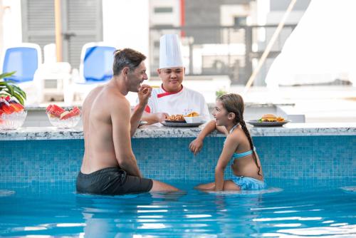 拉斯阿尔卡麦KAY Homes的坐在游泳池里的男人和年轻女孩