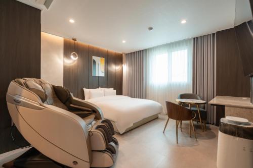 堤川市Jecheon Hound Hotel的配有一张床和一把椅子的酒店客房