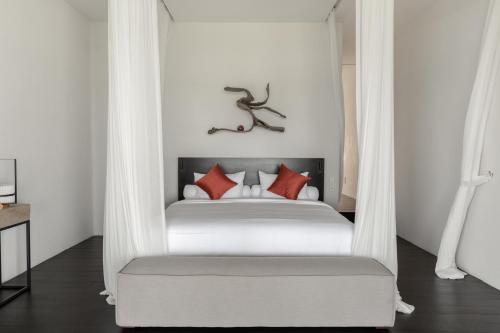 特贾库拉The Jing的卧室配有带红色枕头的白色床