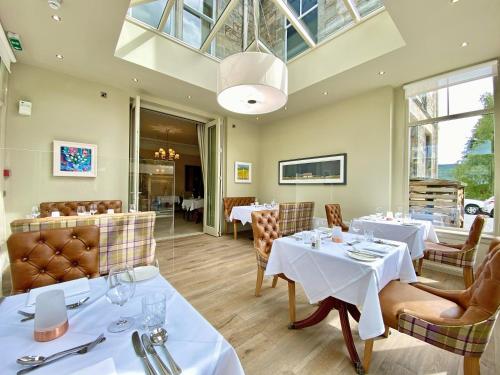 皮特洛赫里Knockendarroch Hotel的餐厅设有桌椅和玻璃天花板