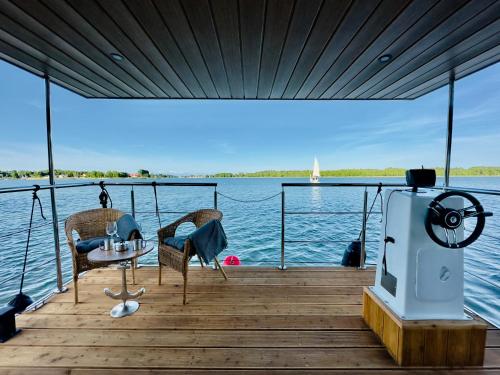 吉日茨科Domki na wodzie - Resort 36 Houseboats的一个带两把椅子和一张桌子的木甲板