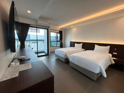 春武里GEEN Hotel Chonburi的一间卧室配有两张床和一台平面电视