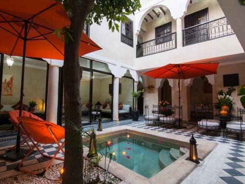 马拉喀什橙色乐贝儿庭院旅馆的一座带橙色遮阳伞的建筑中的游泳池