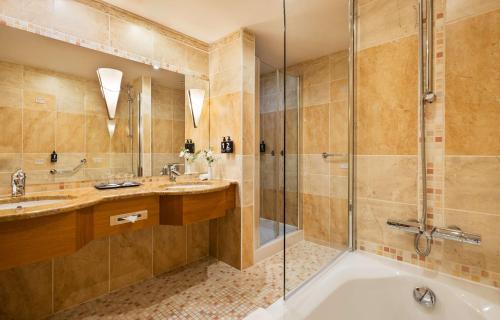 布拉格Lindner Hotel Prague Castle, part of JdV by Hyatt的带浴缸、两个盥洗盆和淋浴的浴室。