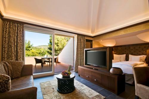 波塔尔斯诺斯Lindner Hotel Mallorca Portals Nous, part of JdV by Hyatt的一间卧室配有一张床、一台电视和一个阳台