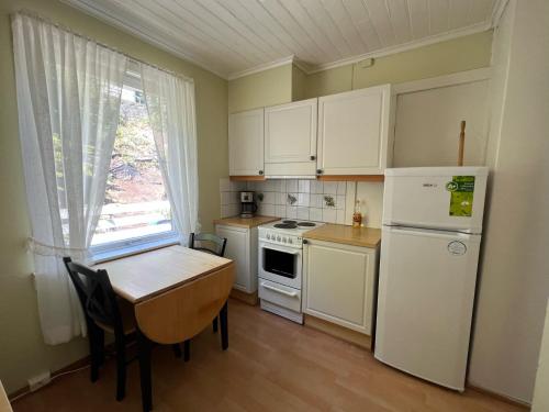 奥达Odda City Apartments的厨房配有白色橱柜、桌子和冰箱。