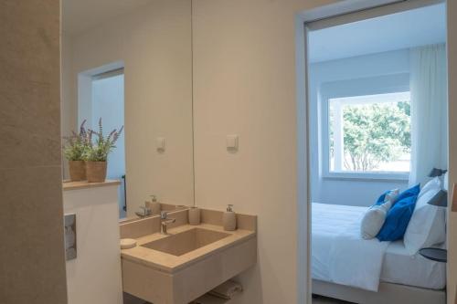 卡尔卡维洛斯NEW Estrela da Praceta Apt w/ 3 Suites & Oceanview的一间带水槽的浴室和一张带镜子的床