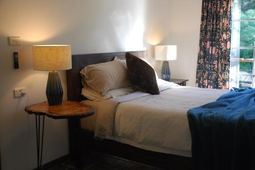 BilpinThe Bower at Wildside Sanctuary的一间卧室配有一张带两盏灯的床和一扇窗户。