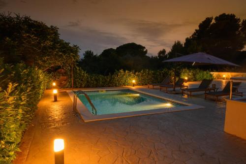 特罗吉尔Villa Vinko的夜间游泳池,提供蜡烛和遮阳伞