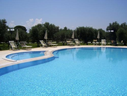 博尔加涅Agriturismo Masseria Baronali的一个带椅子和遮阳伞的大型蓝色游泳池