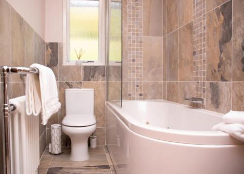 基林3 Bedroom luxury home, hot tub, stunning views of Killin, sitting on the River Dochart的带浴缸、卫生间和盥洗盆的浴室
