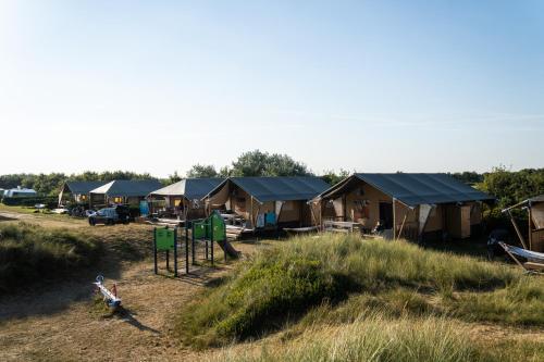 比伦Glamping Ameland的一群帐篷位于田野,设有游乐场