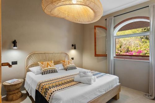 Porto IstanaBaia Dorata beach apartment的一间卧室配有一张带窗户和吊灯的床。