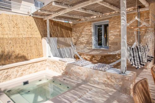 VathíTERRA E SOLE spa suite Aegina的一个带热水浴缸和两把椅子的庭院