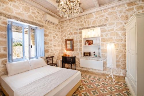 VathíTERRA E SOLE spa suite Aegina的一间卧室配有一张床、一张书桌和一个吊灯。