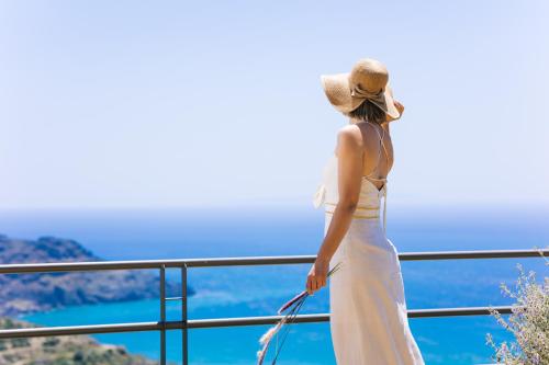 普拉基亚斯Villa Stella Suites的穿着白色衣服和帽子的女人,看着大海