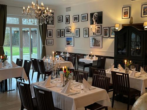格罗瑙dS Hotel Restaurant Gronau的餐厅配有白色的桌椅和吊灯