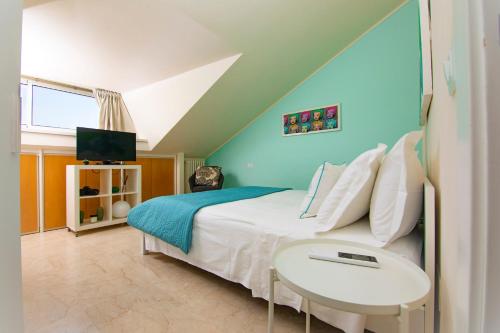 里乔内Prime blue suite - Giardini的一间卧室配有一张带桌子的床和一台电视。