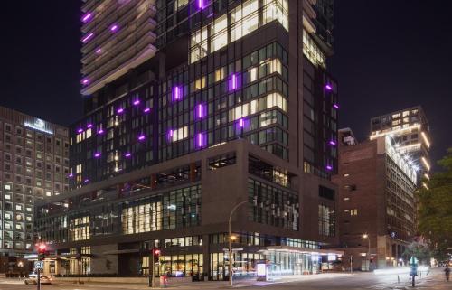 蒙特利尔HONEYROSE Hotel, Montreal, a Tribute Portfolio Hotel的一座高大的建筑,上面有紫色的灯