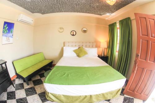 尼格瑞尔Kaiser Hotel- Negril West End的一间卧室设有绿色的床和绿色长凳