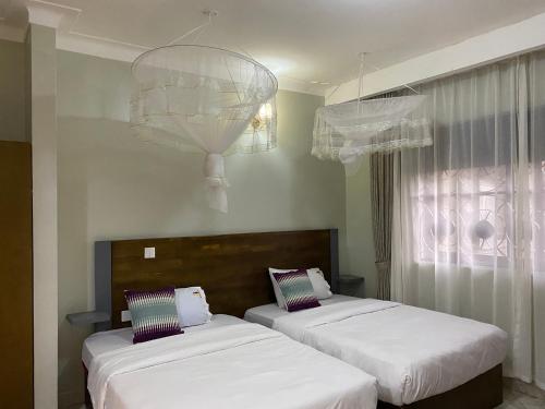 恩德培Tenda Suites and Restaurant的客房设有两张床和吊灯。