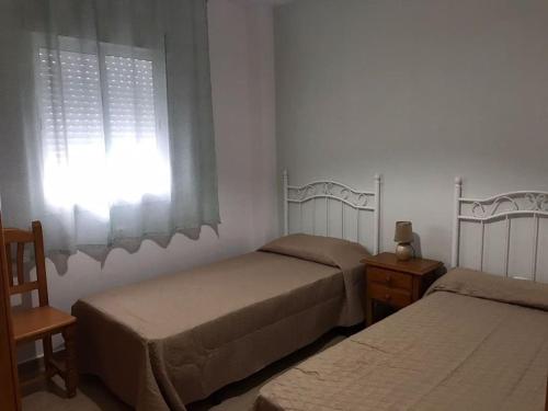 科尼尔-德拉弗龙特拉Apartamento Conil的一间卧室设有两张单人床和一个窗户。