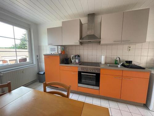 哈尔伯Ferienwohnung Unter den Linden的厨房配有橙色橱柜、水槽和桌子