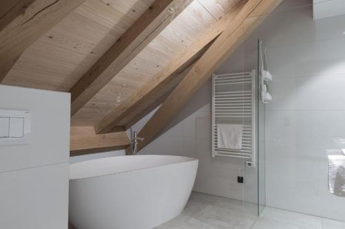 施瓦岑贝格Haus Hof 30的浴室配有白色浴缸和木制天花板