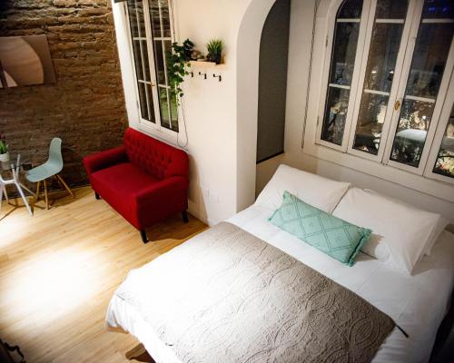 圣地亚哥Loft Nuevo en Santiago, Barrio Lastarria的一间卧室配有一张床和一张红色椅子