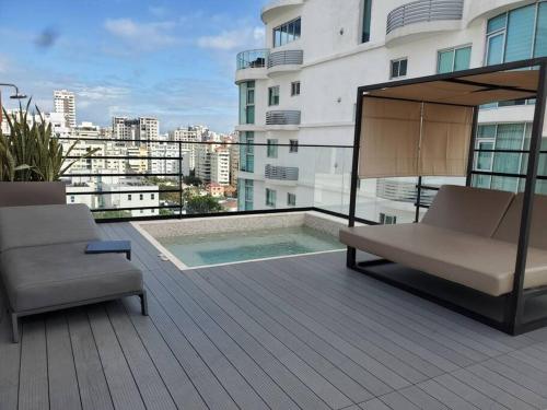 圣多明各Acogedor Apartamento - Regatta Living 2的阳台配有两把椅子,大楼内设有一个游泳池