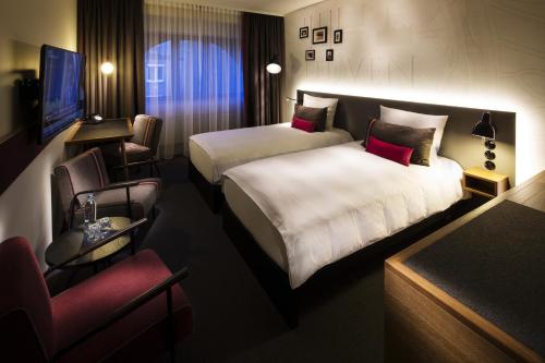 鲁汶pentahotel Leuven的酒店客房,配有两张床和椅子