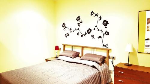 罗列特海岸略雷特海滩公寓 的卧室配有一张墙上鲜花的床