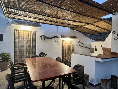 马拉加Casa rural Las Casillas的一间带木桌和椅子的用餐室