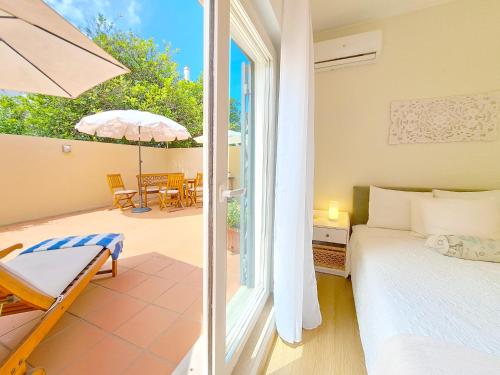 波尔蒂芒Villa Prana Guesthouse, Yoga & Ayurveda的一间卧室配有一张床,庭院配有遮阳伞