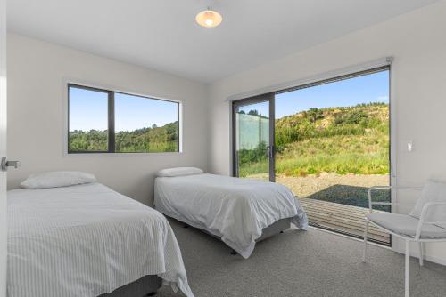 Waipu CoveModern Sanctuary - Waipu Holiday Home的一间白色卧室,配有两张床和窗户